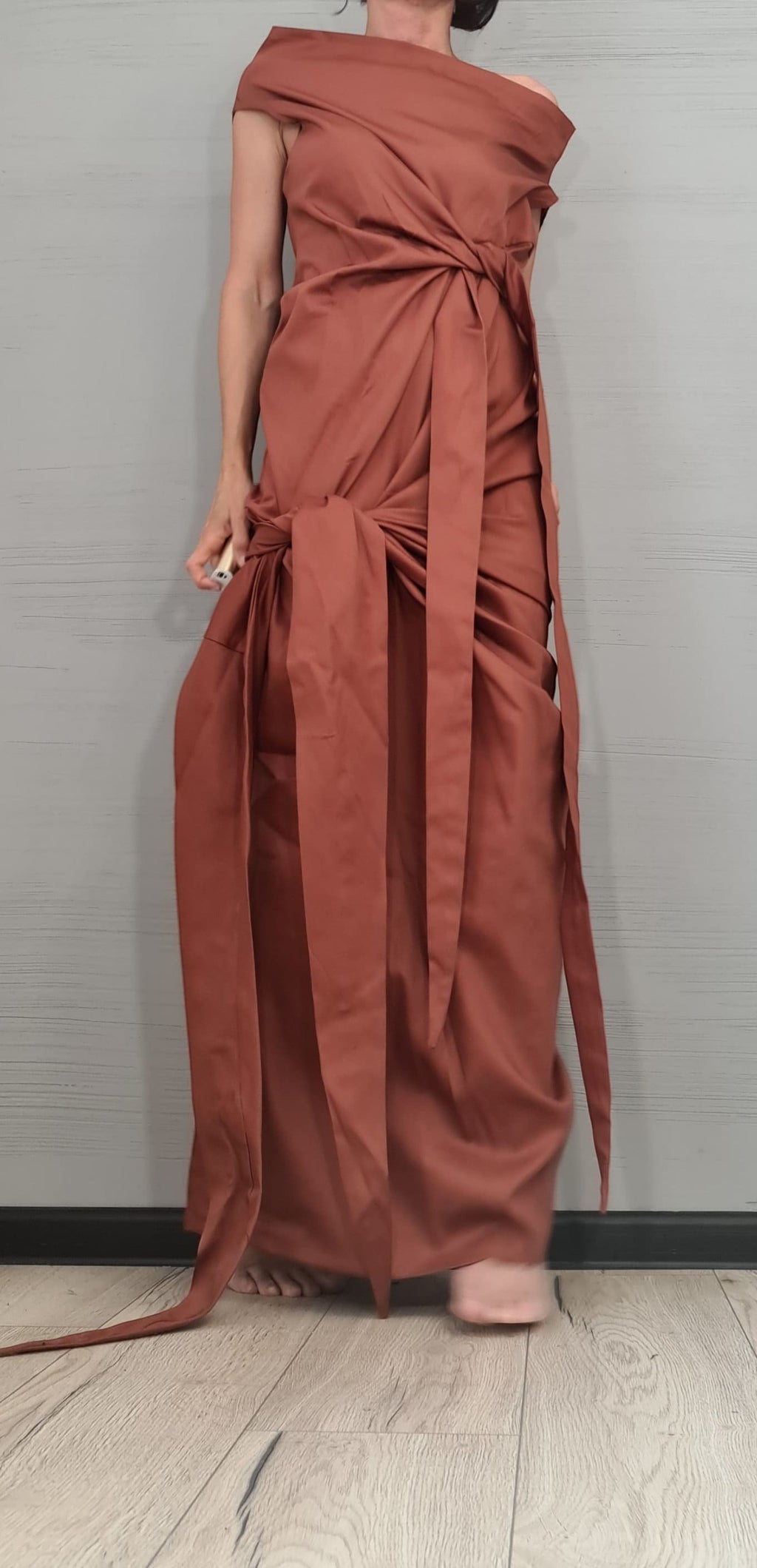 dreSSShoescode rust orange one-shoulder maxi dress with asymmetric draping and tie waist, made of cotton and polyester.